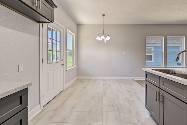 kitchen with sink, light hardwood / wood-style floors, pendant lighting, gray cabinets, and an inviting chandelier