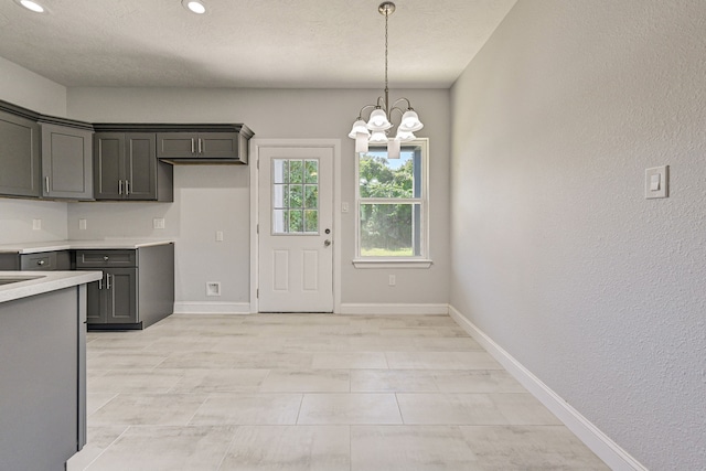 kitchen featuring gray cabinets, a notable chandelier, a textured ceiling, and decorative light fixtures