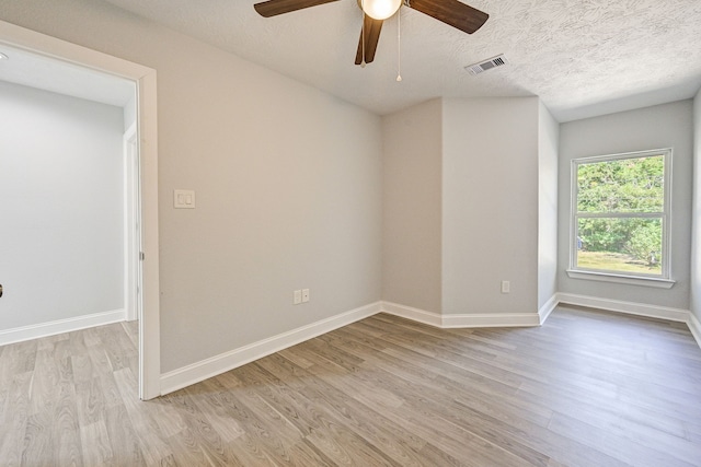 empty room featuring a textured ceiling, light wood-type flooring, and ceiling fan