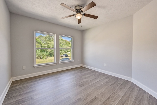 spare room with a textured ceiling, light wood-type flooring, and ceiling fan