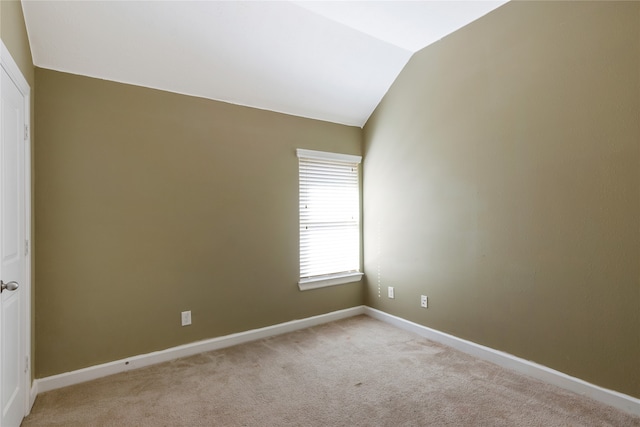 carpeted empty room featuring vaulted ceiling