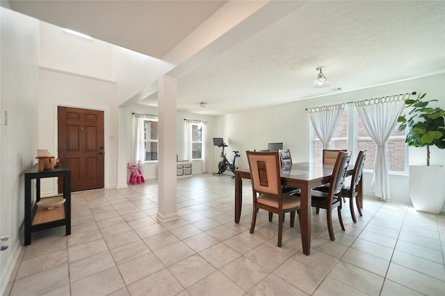 tiled dining room with a textured ceiling and decorative columns