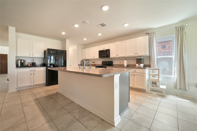 kitchen with black appliances, white cabinets, light tile patterned flooring, and an island with sink