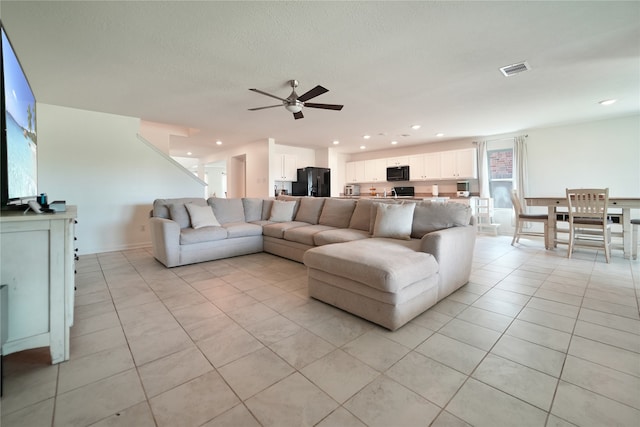 living room featuring a textured ceiling, light tile patterned floors, and ceiling fan