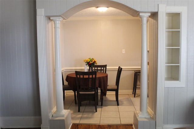 dining room featuring built in shelves, ornate columns, tile patterned flooring, a textured ceiling, and ornamental molding