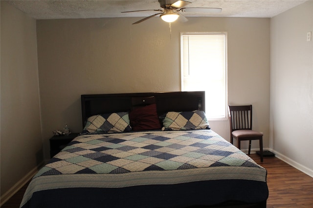 bedroom featuring dark hardwood / wood-style floors, ceiling fan, and a textured ceiling