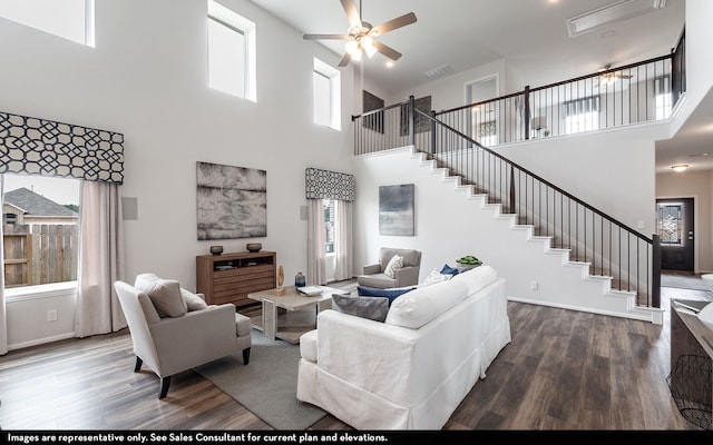 living room featuring ceiling fan, hardwood / wood-style flooring, and a towering ceiling