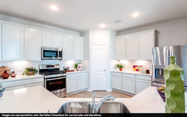 kitchen featuring appliances with stainless steel finishes, sink, light wood-type flooring, and white cabinets