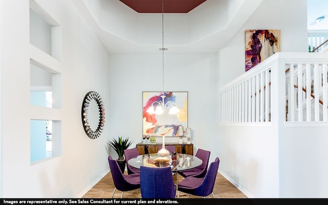 dining room with a towering ceiling, a chandelier, and hardwood / wood-style floors