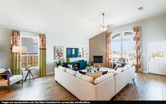 living room featuring hardwood / wood-style floors, vaulted ceiling, and a tiled fireplace