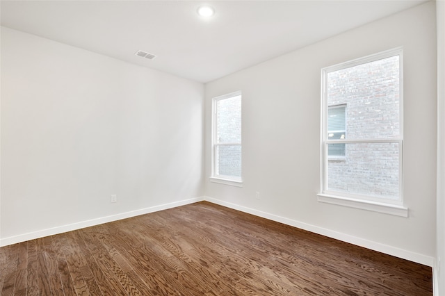 spare room with a healthy amount of sunlight and dark wood-type flooring