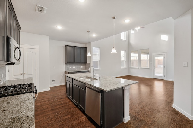 kitchen with stainless steel appliances, dark brown cabinetry, sink, and a kitchen island with sink