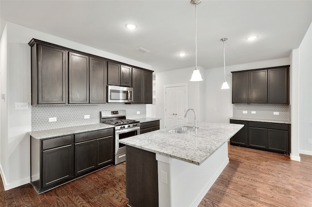 kitchen with decorative backsplash, an island with sink, hanging light fixtures, stainless steel appliances, and sink