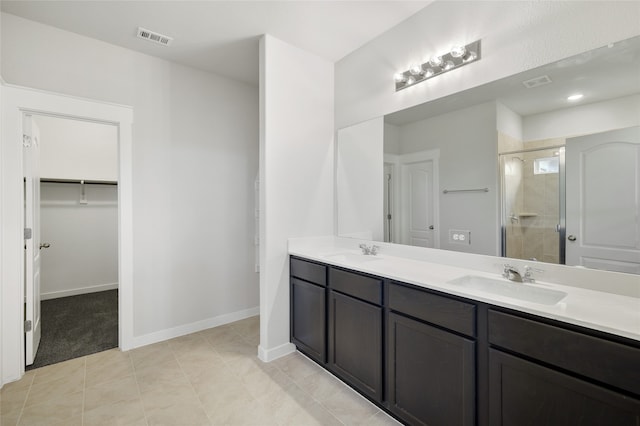 bathroom with a shower with door, vanity, and tile patterned floors