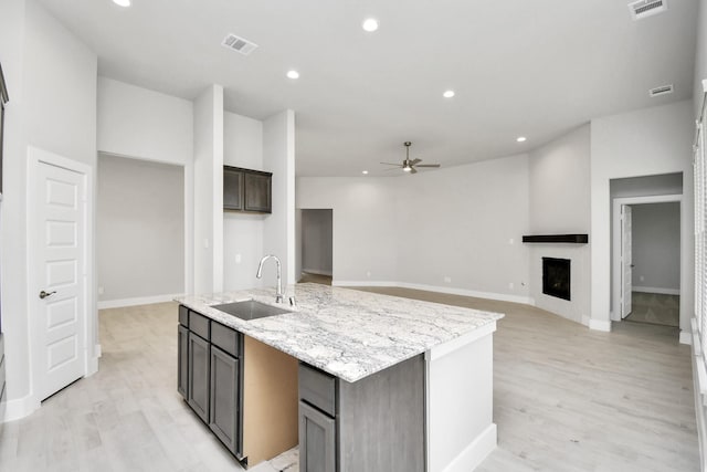 kitchen featuring visible vents, a ceiling fan, light wood-style floors, and a sink