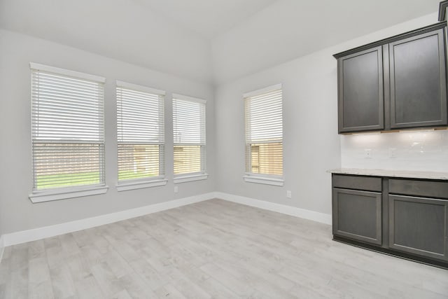 unfurnished dining area featuring baseboards and light wood-style flooring
