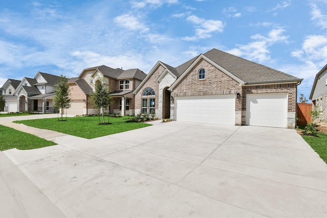 french provincial home featuring driveway, a front yard, an attached garage, and brick siding