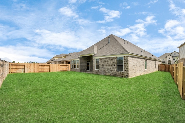 back of property with roof with shingles, a yard, a fenced backyard, and brick siding