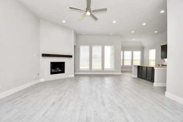 unfurnished living room with baseboards, recessed lighting, light wood-style flooring, and a sink