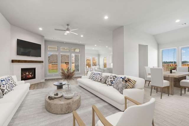 living area with a glass covered fireplace, visible vents, recessed lighting, and light wood-style flooring