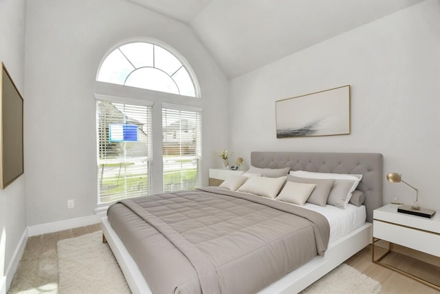 bedroom with baseboards, multiple windows, and lofted ceiling