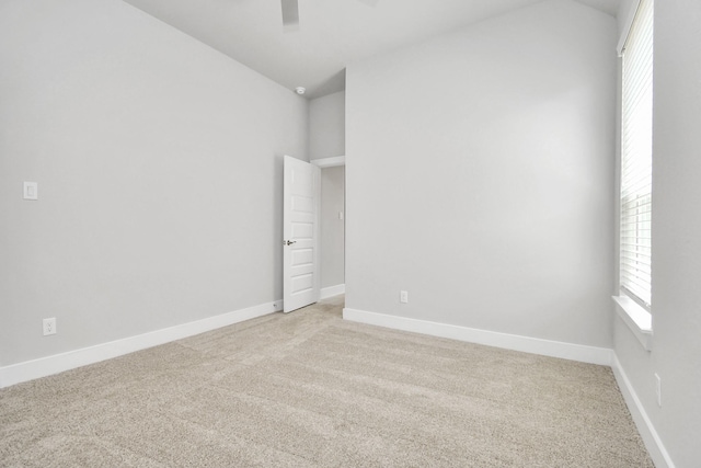 unfurnished room with baseboards, light carpet, ceiling fan, and vaulted ceiling