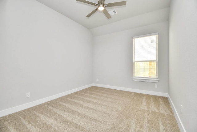 carpeted empty room with visible vents, a ceiling fan, vaulted ceiling, and baseboards