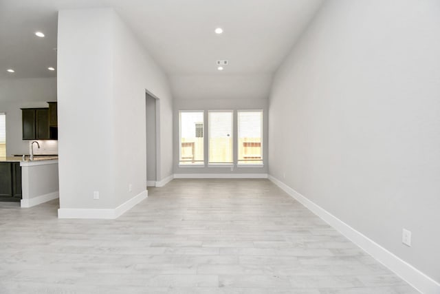empty room with baseboards, recessed lighting, a sink, and plenty of natural light