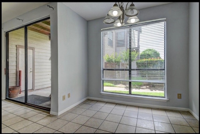 spare room with light tile patterned flooring and a chandelier