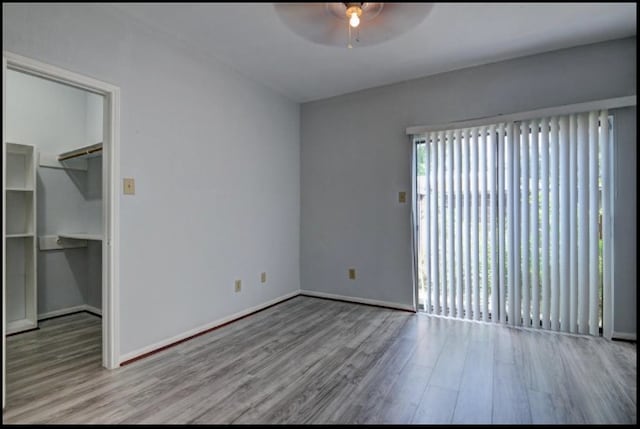 unfurnished bedroom with a closet, light hardwood / wood-style flooring, a spacious closet, and ceiling fan