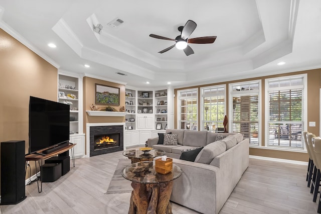 living room with light hardwood / wood-style flooring, ceiling fan, crown molding, and a raised ceiling