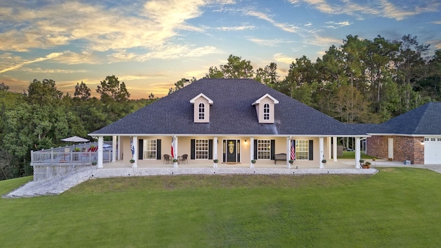 view of front of property featuring covered porch, a garage, and a lawn