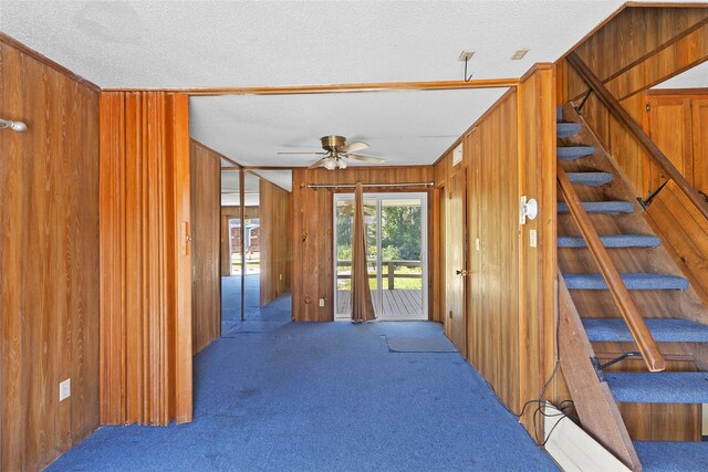 interior space with wood walls, carpet, and a textured ceiling