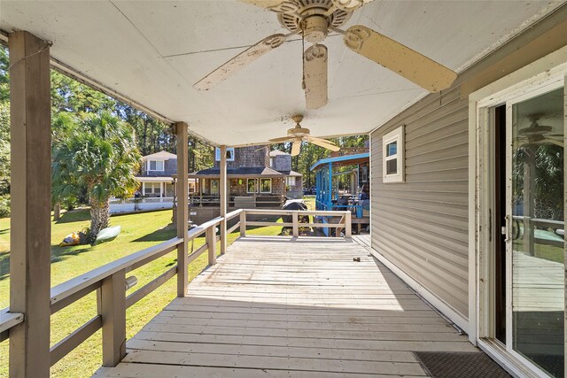 wooden terrace featuring a lawn and ceiling fan