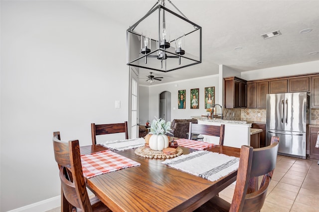 tiled dining area featuring ceiling fan with notable chandelier