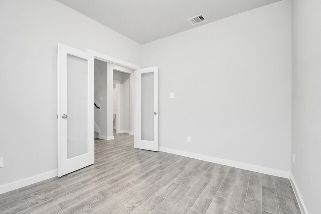 unfurnished room with french doors and light wood-type flooring