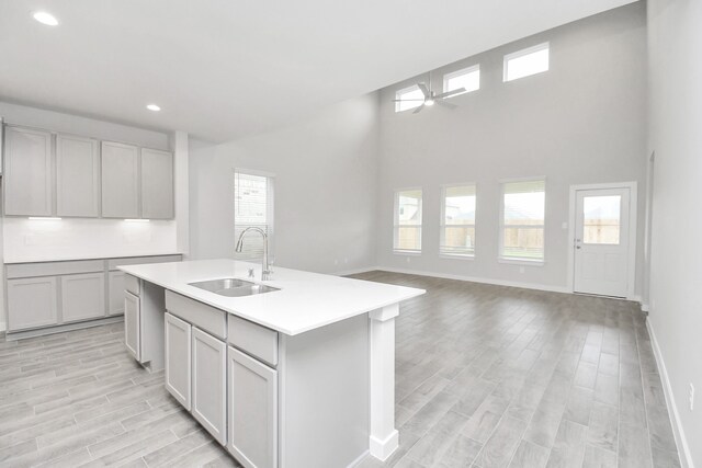 kitchen with a healthy amount of sunlight, sink, a center island with sink, and gray cabinets