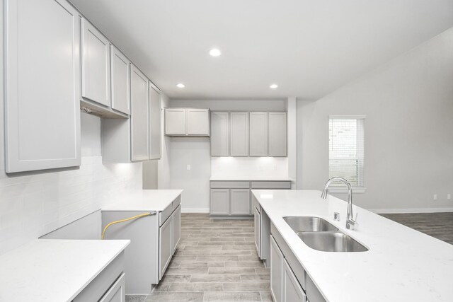 kitchen featuring sink, decorative backsplash, gray cabinetry, and light wood-type flooring