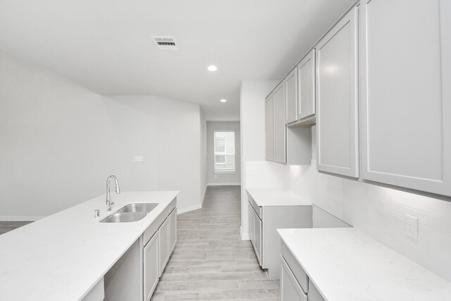 kitchen featuring tasteful backsplash, sink, and light wood-type flooring