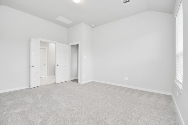 unfurnished bedroom featuring light carpet and vaulted ceiling