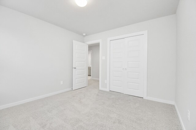 unfurnished bedroom with a closet and light colored carpet