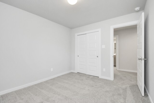 unfurnished bedroom with a closet and light carpet