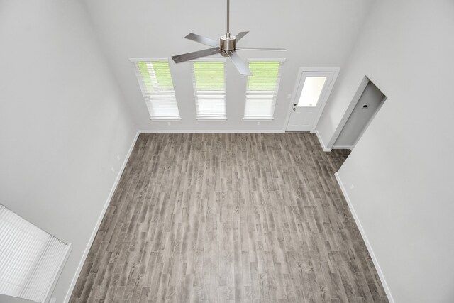 unfurnished living room featuring ceiling fan, wood-type flooring, and plenty of natural light