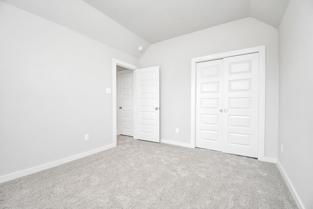 unfurnished bedroom featuring a closet, lofted ceiling, and light colored carpet