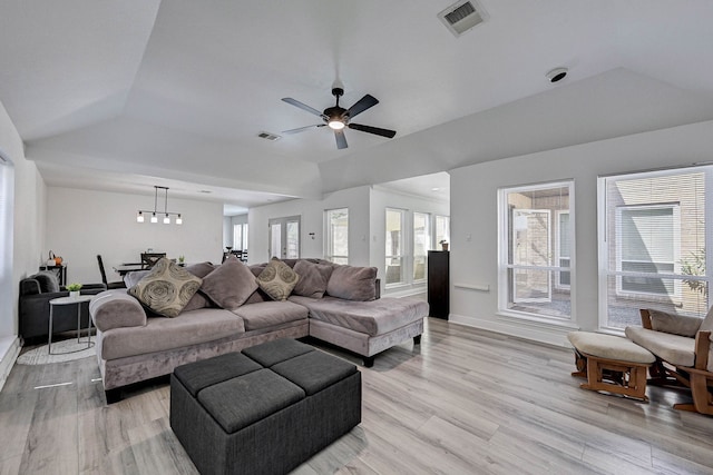 living room featuring ceiling fan, a tray ceiling, and light wood-type flooring