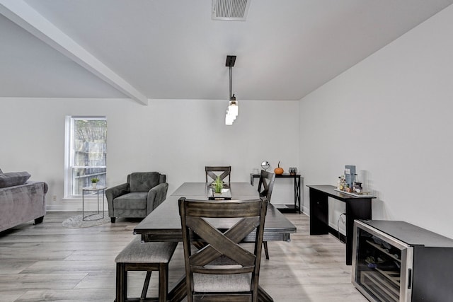 dining space with beamed ceiling, light wood-type flooring, and beverage cooler