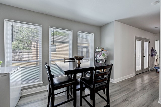 dining area with french doors and light hardwood / wood-style flooring