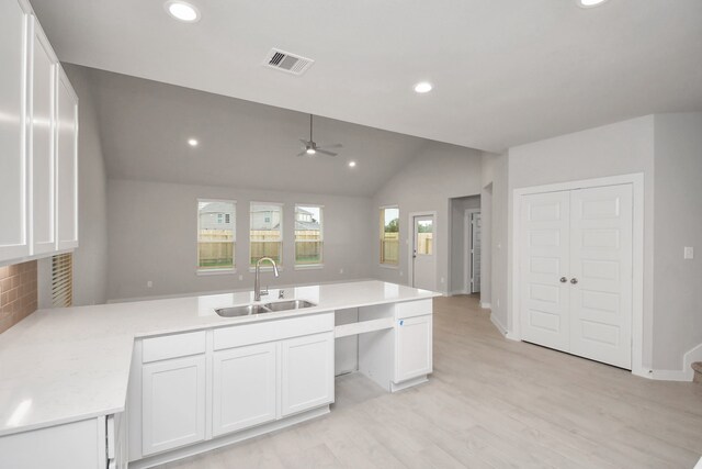 kitchen featuring sink, vaulted ceiling, kitchen peninsula, and white cabinetry