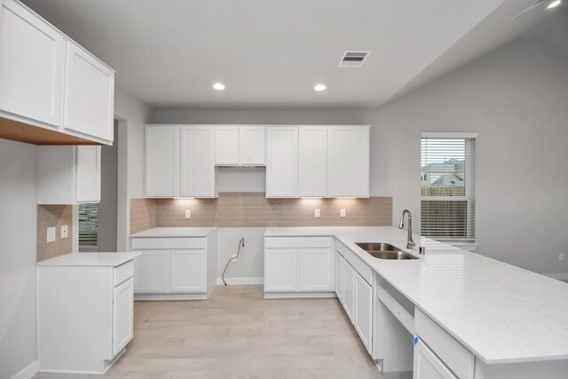 kitchen with sink, backsplash, white dishwasher, white cabinetry, and light hardwood / wood-style flooring