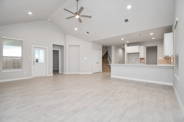 unfurnished living room with high vaulted ceiling, light wood-type flooring, and ceiling fan